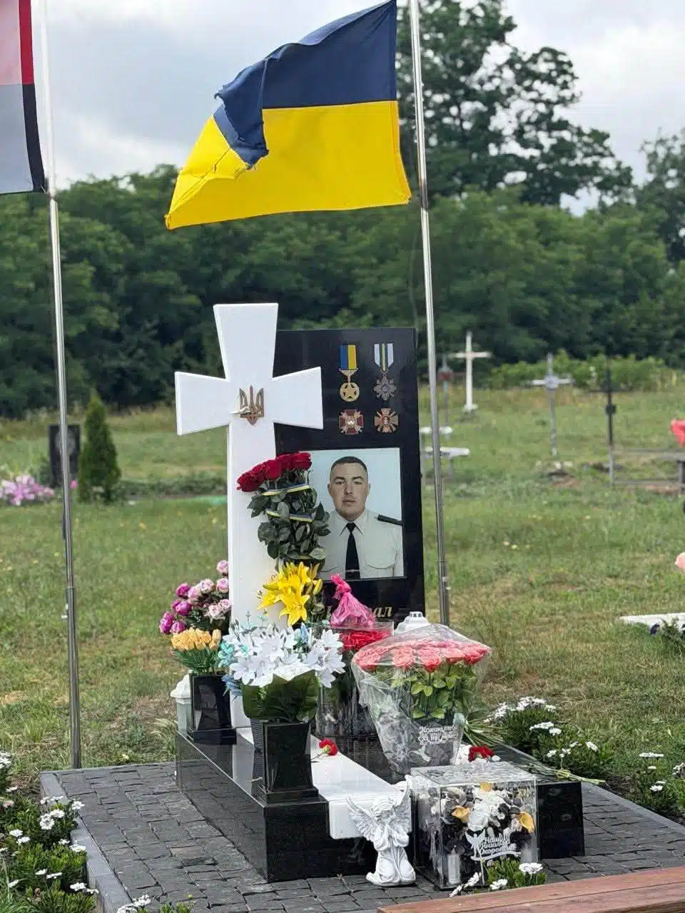 Могила військового з прапором України, білим хрестом і портретом у формі
