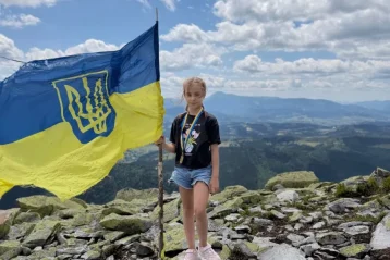 Дівчинка на кам’яній вершині Карпат тримає прапор України з тризубом