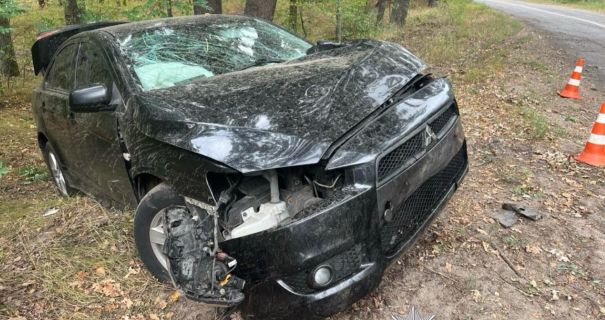 Розбитий чорний Mitsubishi Lancer на узбіччі лісової дороги біля конусів