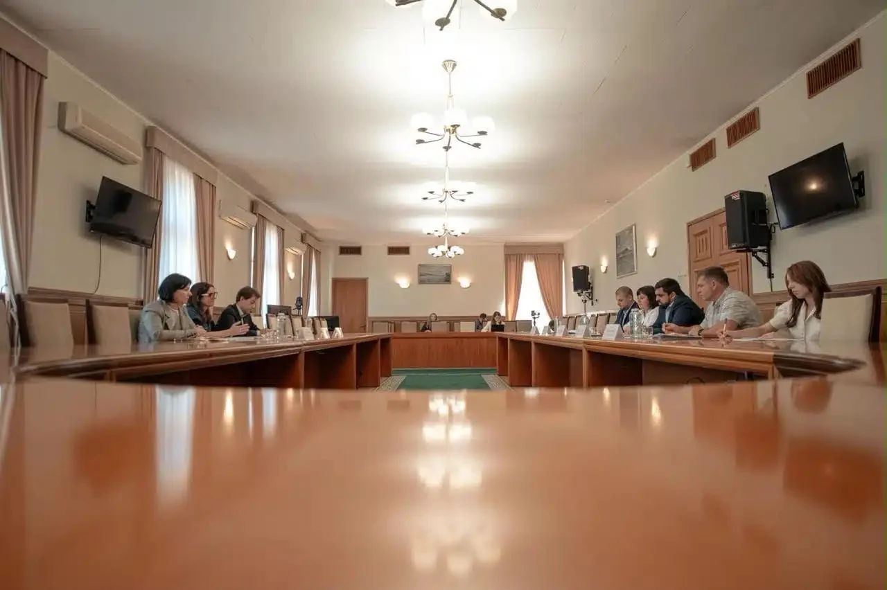 Офіційна нарада людей за довгим столом у залі адміністрації