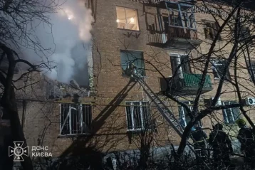 Рятувальники на драбині біля пошкодженого цегляного будинку з димом у Києві вночі
