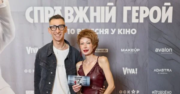 Чоловік і жінка позують біля банера фільму Справжній герой з квитком