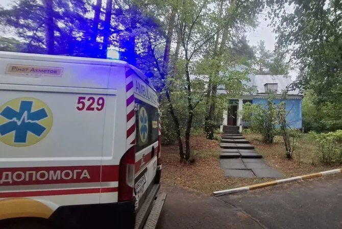 Швидка допомога біля блакитного будинку серед дерев